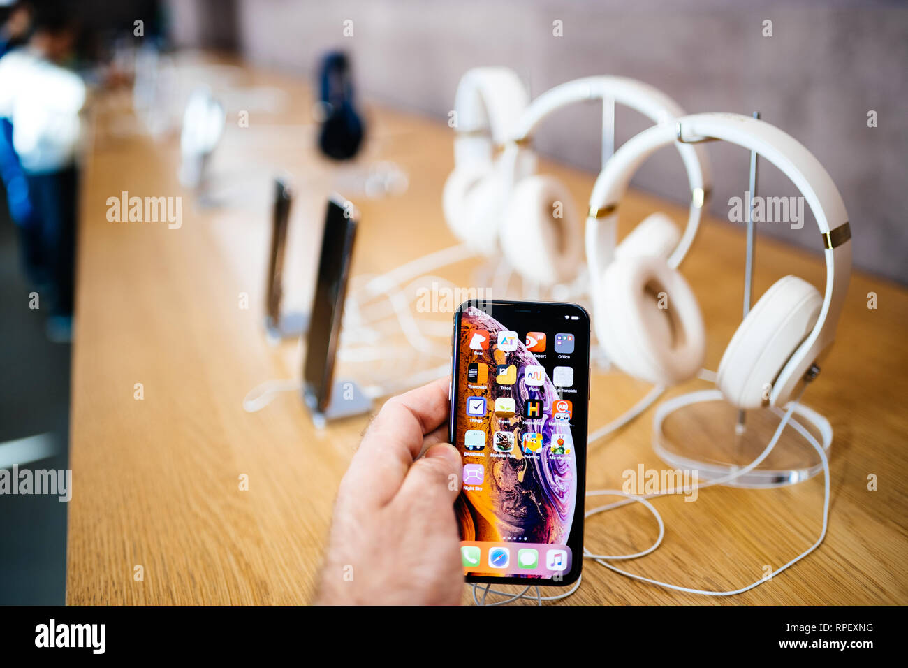 PARIS, FRANCE - OCT 26, 2018: Man hand holding new iphone Xs Xr Max with Apple Music app and multiple wireless bluetooth headphones Beats By Dr Dre Studio 3 Stock Photo