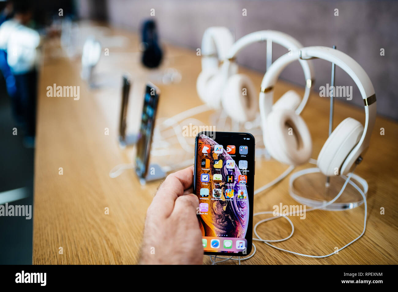 PARIS, FRANCE - OCT 26, 2018: Man hand holding new iphone Xs Xr Max with Apple Music app and multiple wireless bluetooth headphones Beats By Dr Dre Studio 3 - perspective view Stock Photo