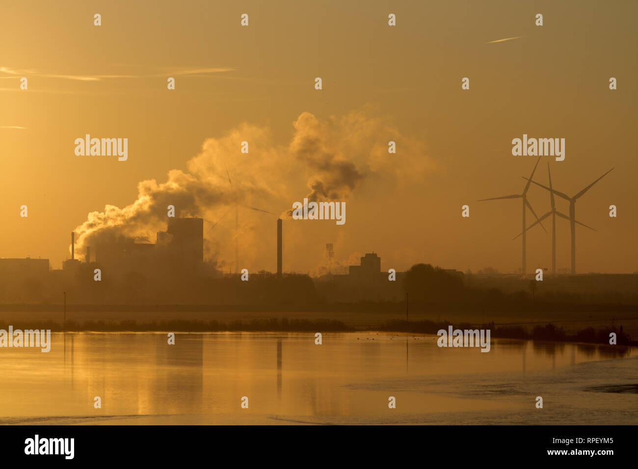 Wind turbines and industrial buildings at sunrise Stock Photo
