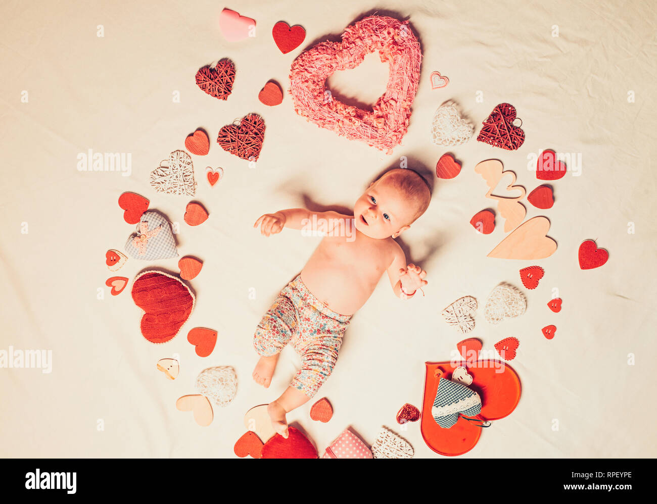 Love of my life. Childhood happiness.Valentines day. Sweet little baby. New life and birth. Family. Child care. Small girl among red hearts. Love Stock Photo