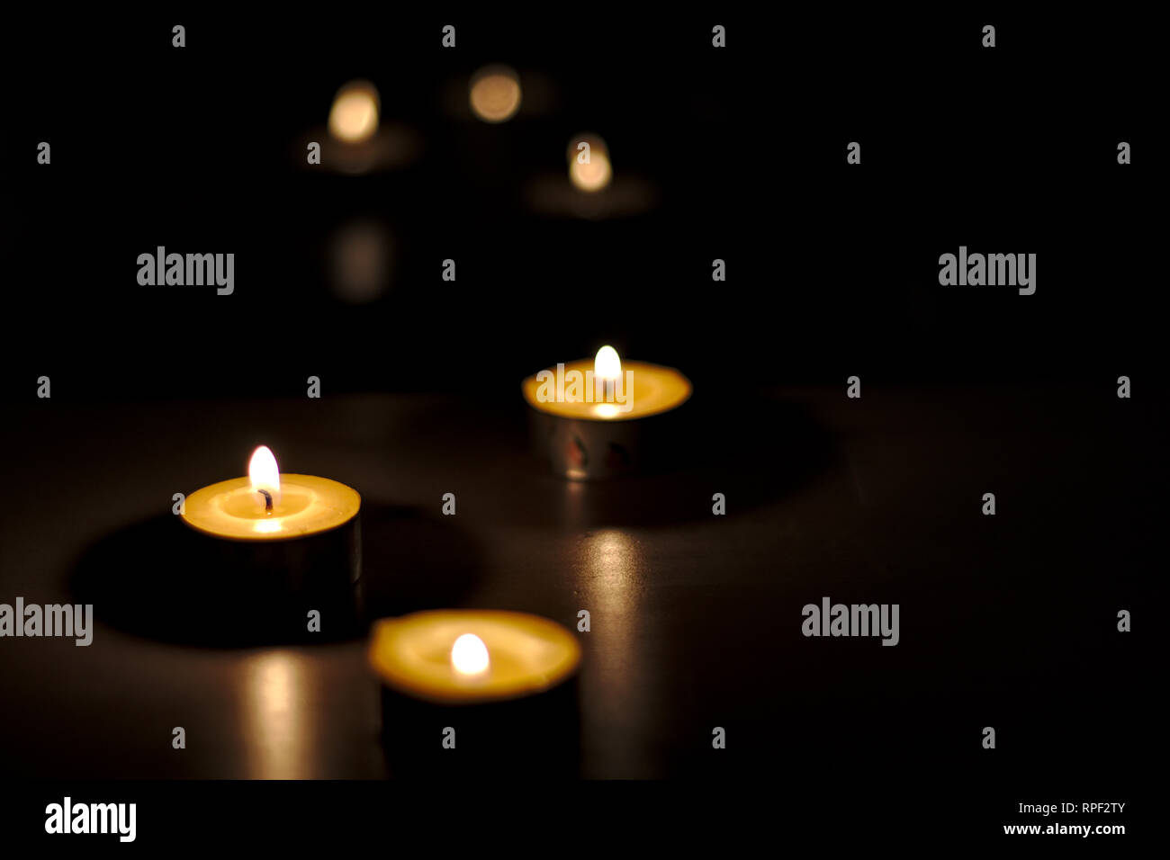 Playing with a minimum of light and bokeh effect, candles lights are reflecting shadows and toughts. Stock Photo