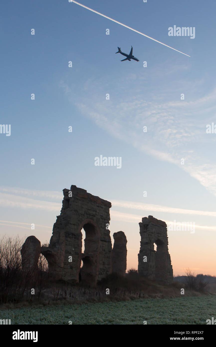 ROME -  Ruins of an aqueduct with a plane flying above it in the early morning at the Parco degli Acquedotti. Stock Photo