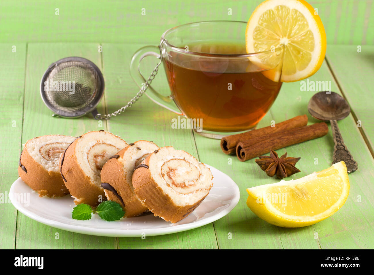 Biscuit swiss roll with a cup of tea on green wooden background Stock ...