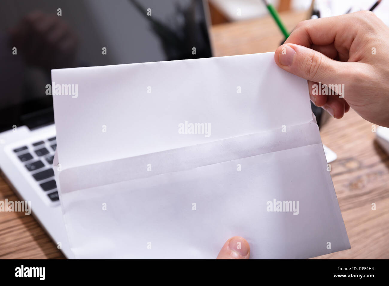 Elevated View Of A Person Removing Paper From Envelope Over Office Desk