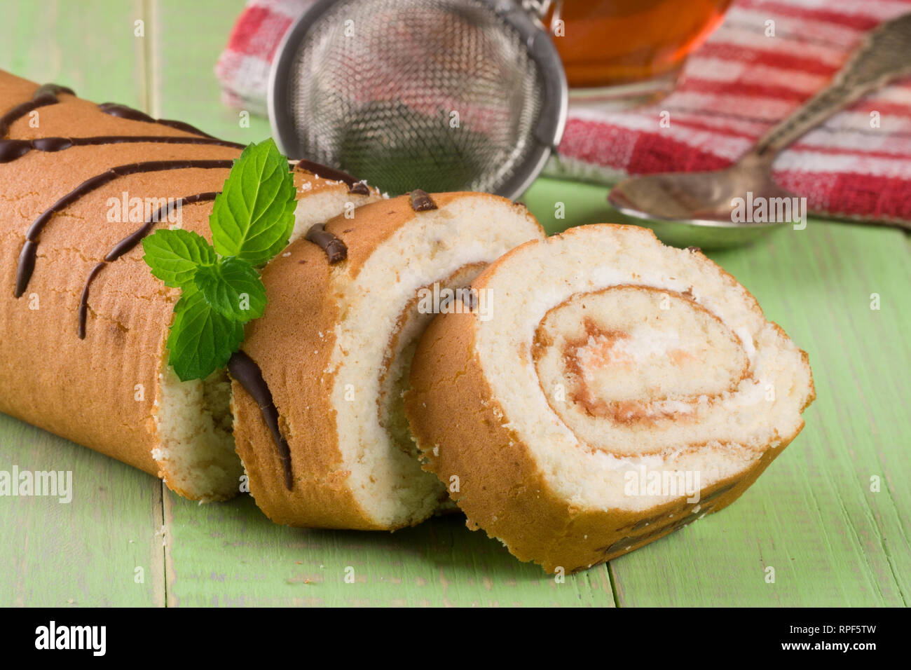 Biscuit swiss roll on green wooden background Stock Photo