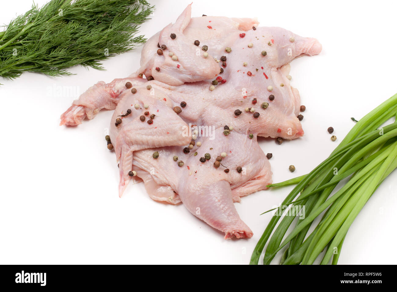 raw chicken carcass with peppercorns and greenery isolated on white