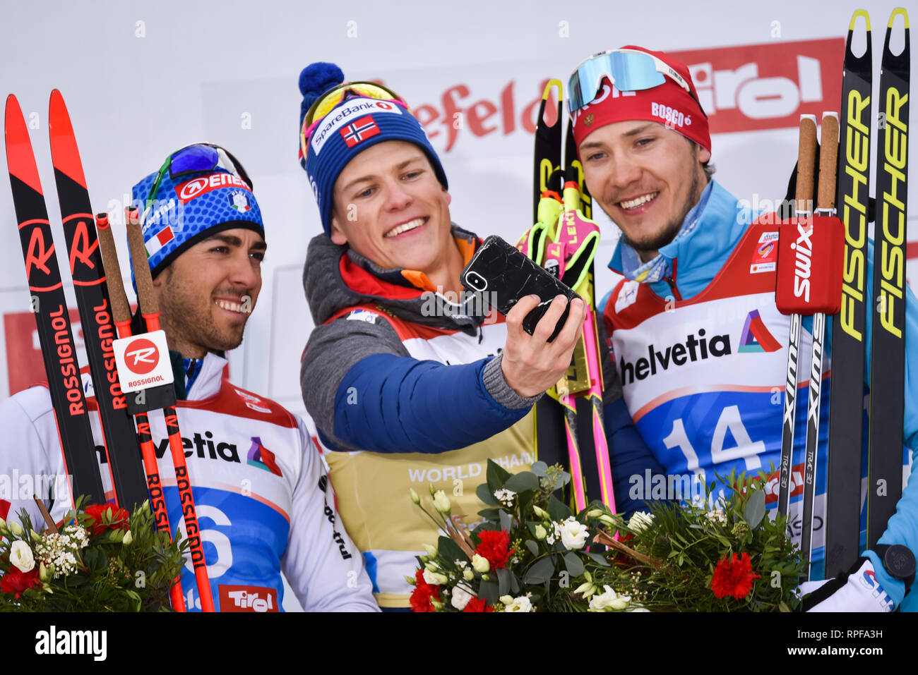 Seefeld, Austria. 21st Feb, 2019. Norway's Johannes Hoesflot Klaebo, center, takes a selfie with fellow racers on the podium, Frederico Pelligrino, Italy, left, and Gleb Retivykh of Russia after the men's 1.6-k freestyle sprint race at the 2019 world nordic ski championships. Klaebo won; Pelligrino was second, Retivykh third. Credit: John Lazenby/Alamy Live News Stock Photo