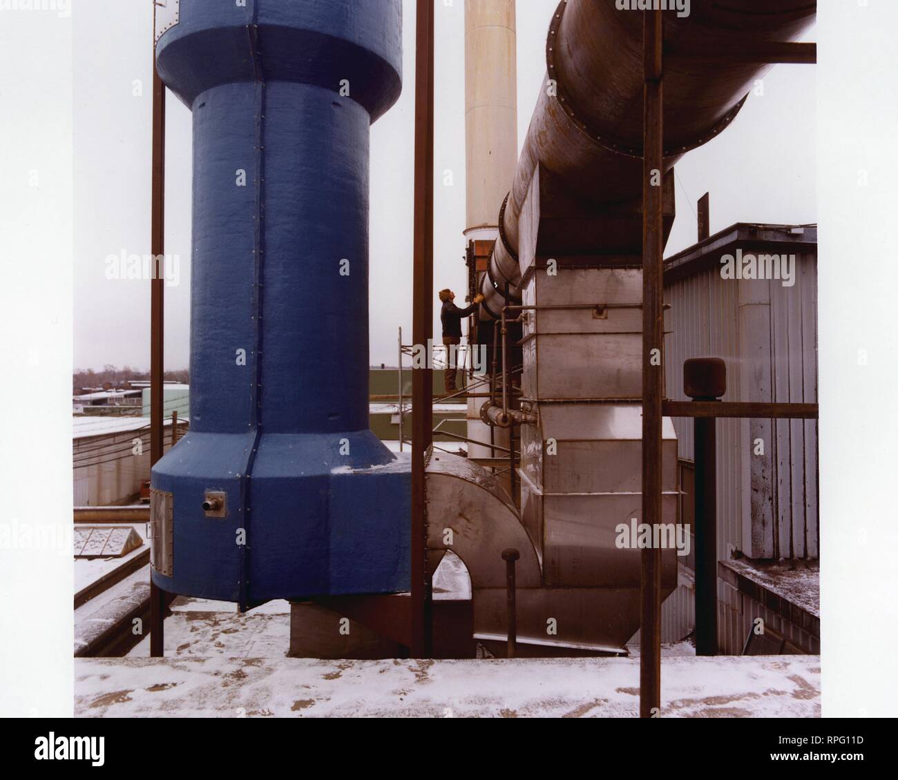 A man stands in profile, on a snowy day, on a rooftop next to a heat extractor, 1995. Image courtesy US Department of Energy. () Stock Photo