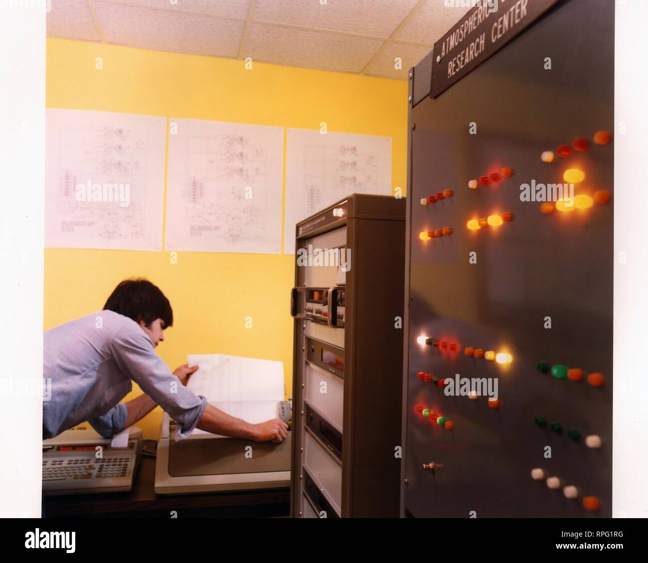 An employee leans over to pull a data sheet from a printer in a facility analyzing energy efficiency at a Jolly Tiger Restaurant in Albany, New York, 1990. Image courtesy US Department of Energy. () Stock Photo