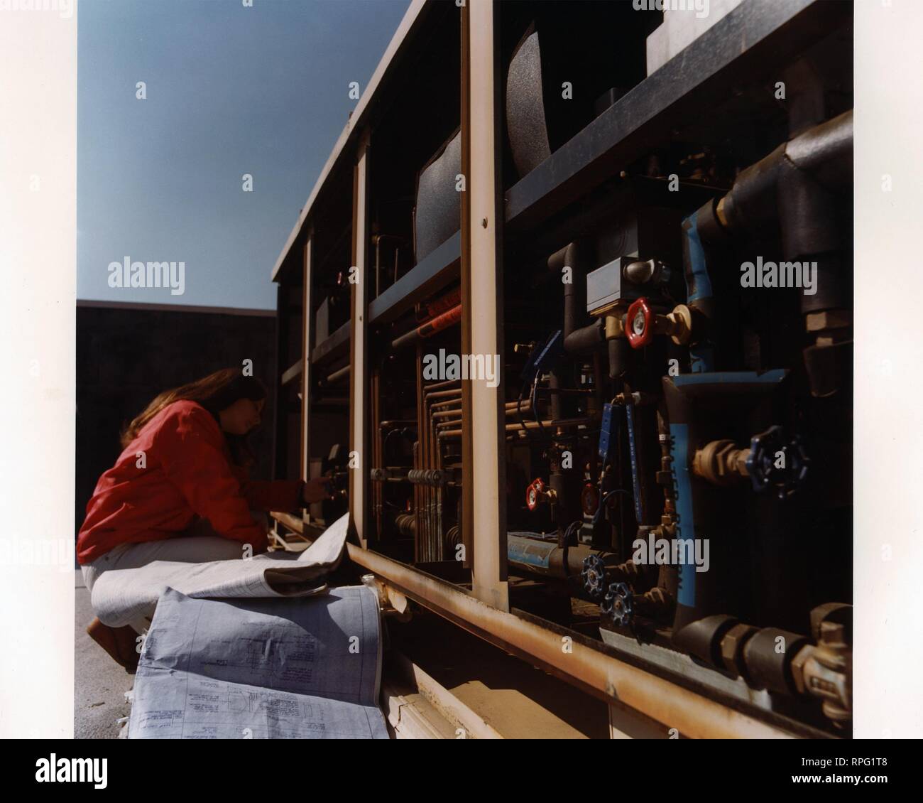 Profile view of a female engineer crouching on a roof to observe the