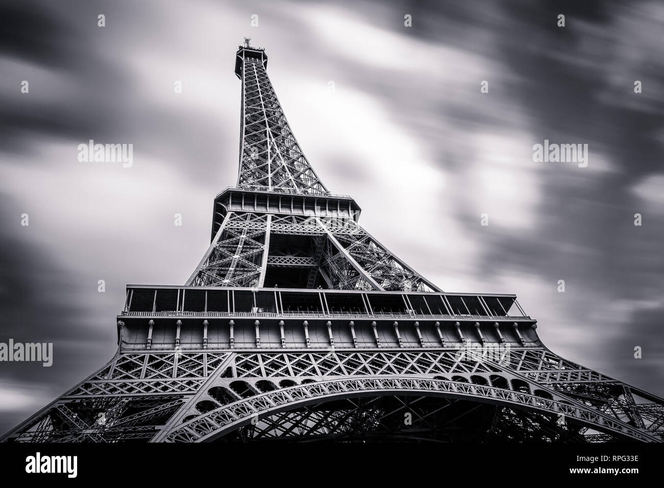 View at the Eiffel tower from below. Long exposure with clouds stretched in the sky. Black and white. Paris, France Stock Photo