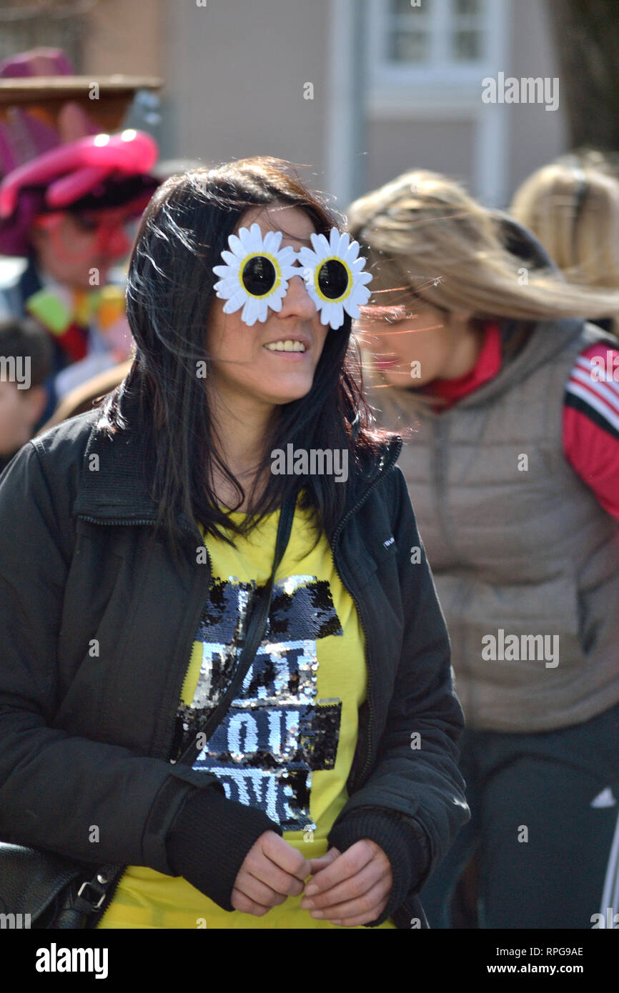 Young woman walking down the street during carnival. Young woman in flower glasses, Svilajnac, Serbia, Europe Stock Photo