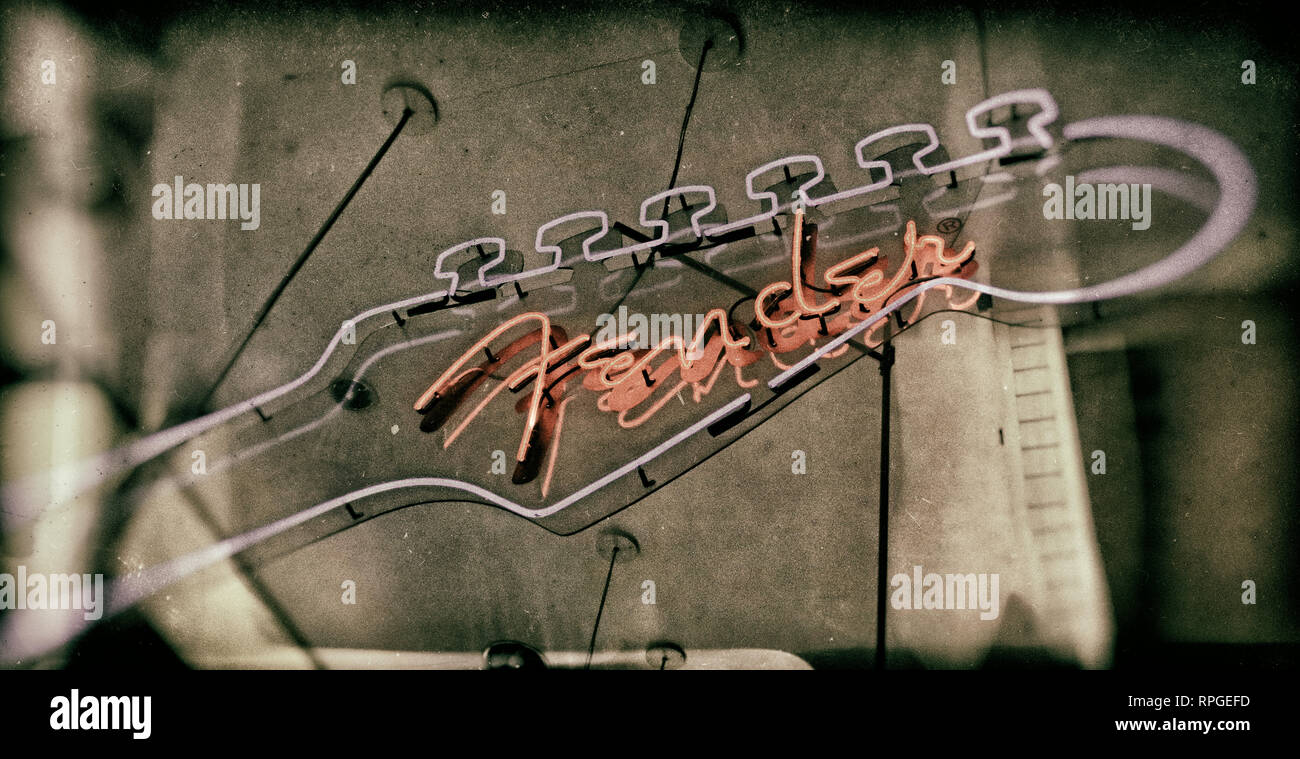 Distressed Black White hand colored Fender Neon Sign in a music instruments store, in blue and red Stock Photo