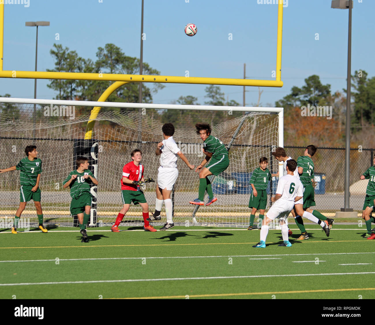 Players jump high in the air on a corner kick in high school boys