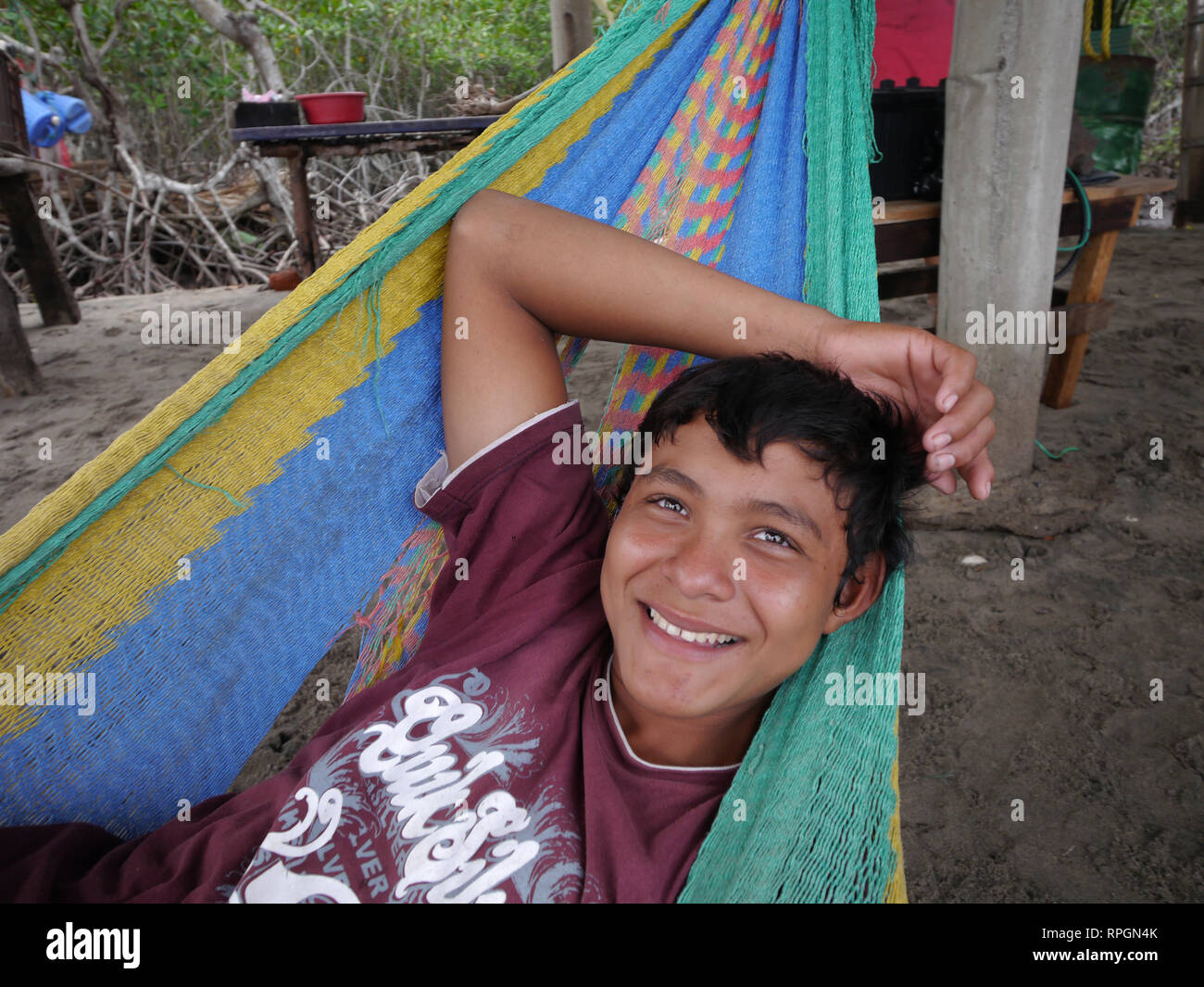 El Salvador  ADECHEPET project. (associascion de Desarrollo Comunal Hermanos Residentes en el Exterior Puerto El Triunfo). Visiting Fishermen on the nearby Isla El Espiritu Santo. They are IAF beneficiaries who had help with nets and outboard motors. Young fisherman, Julio Cesar (15), relaxes on a hammock. Stock Photo