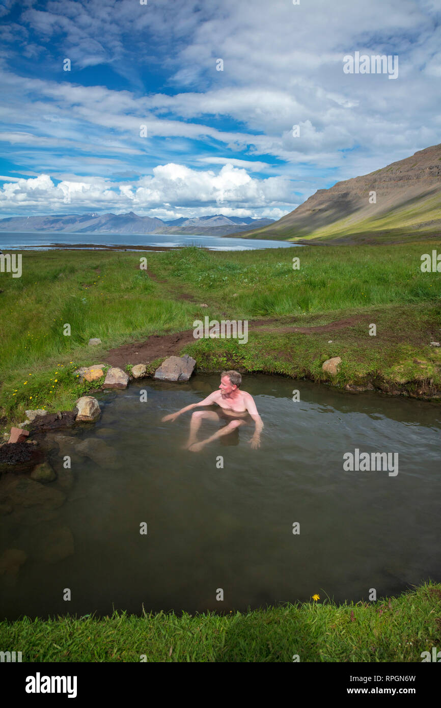 Swimmer taking a dip in Reykjafjardarlaug geothermal pool, beside Arnarfjordur fjord. Westfjords, Iceland. Stock Photo
