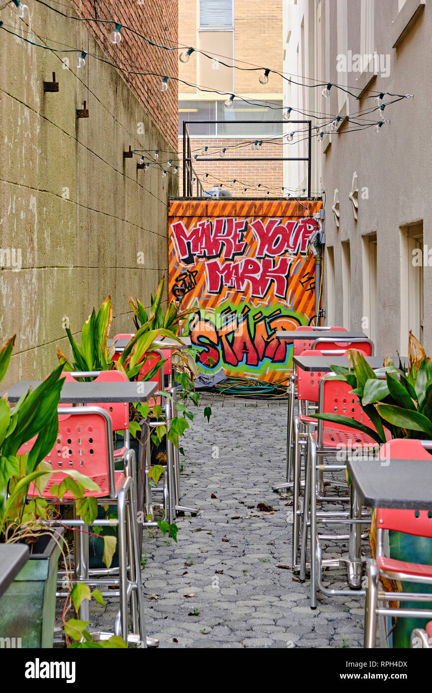 Empty outdoor restaurant courtyard for a bar or outdoor dining with a brightly painted wall and high top tables in Montgomery Alabama, USA. Stock Photo