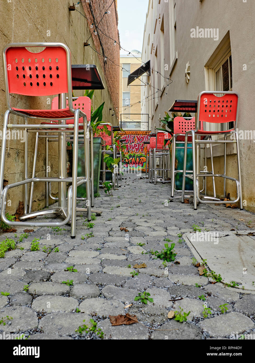 Empty outdoor restaurant courtyard for a bar or outdoor dining with a brightly painted wall and high top tables in Montgomery Alabama, USA. Stock Photo