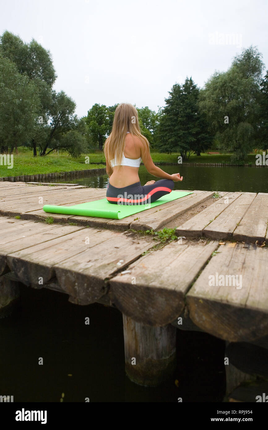 girl in a lotus pose sits with her back to the Yoga in nature Stock Photo - Alamy