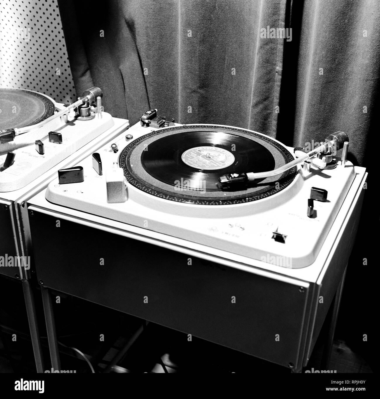 Record player in the televison studio control room, 1958.  Yleisradion televisiotoiminnan alkuvaiheet. Pasilan alastudion äänitarkkaamossa on  kaksi levysoitinta. Lp-levy pyörii levysoittimessa. Äänilevyä soitetaan. Stock Photo