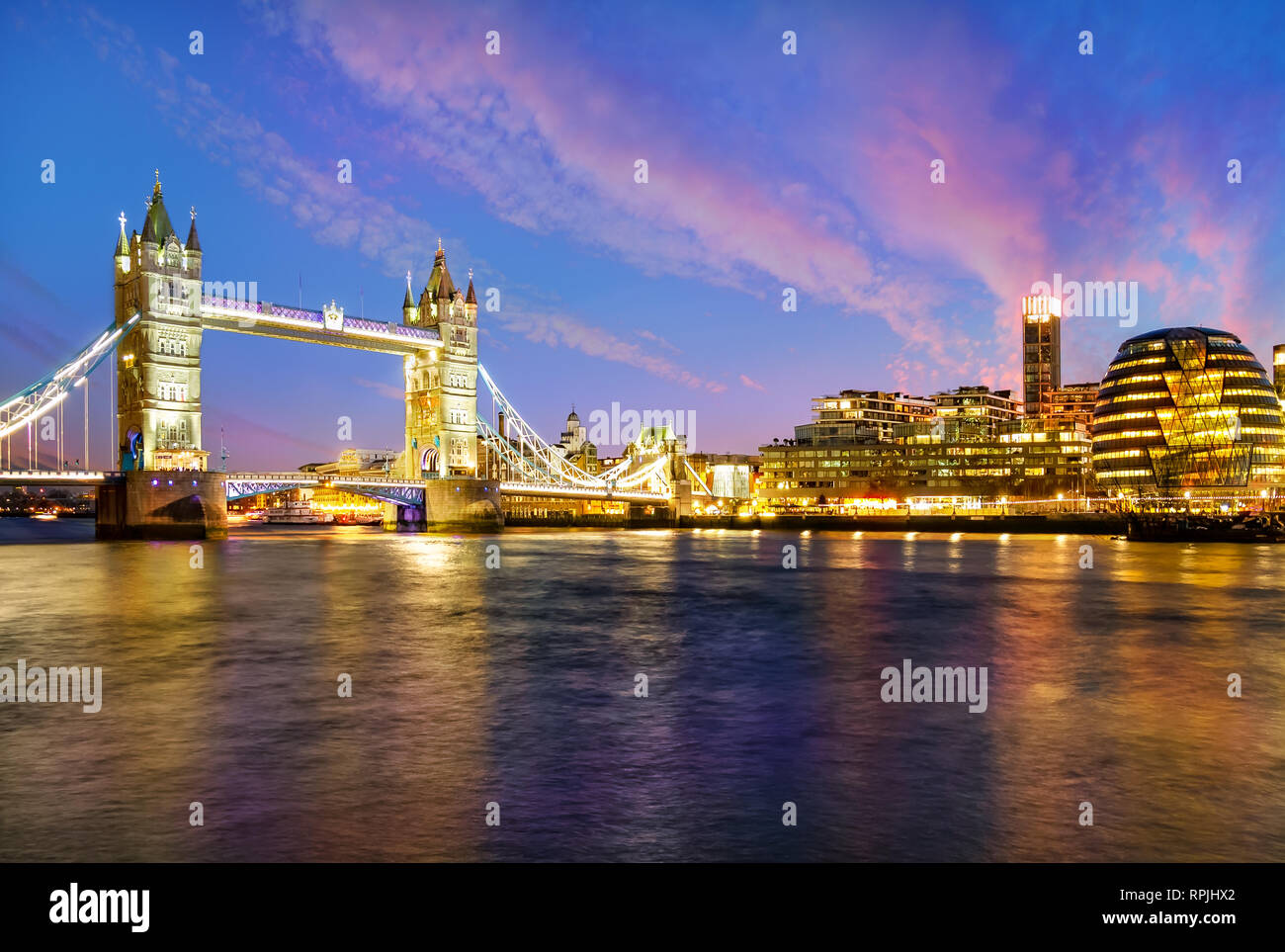 London cityscape at night with famous Tower Bridge illuminated and reflected in Thames river in England - UK Stock Photo