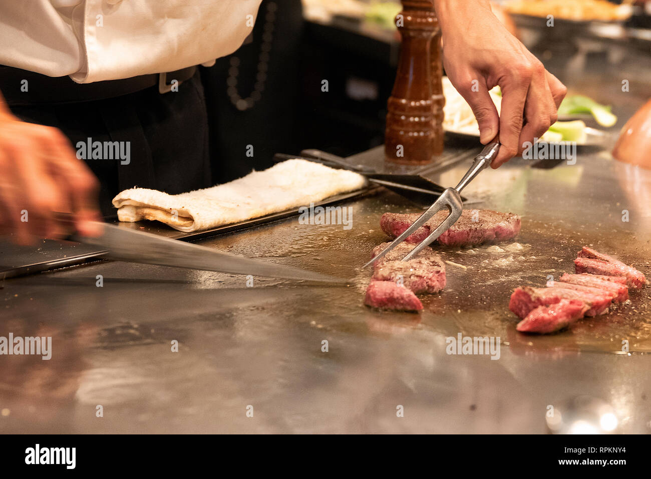 Chef at teppenyaki restaurant in Tokyo, Japan slicing Kobe beef on cooking surface Stock Photo