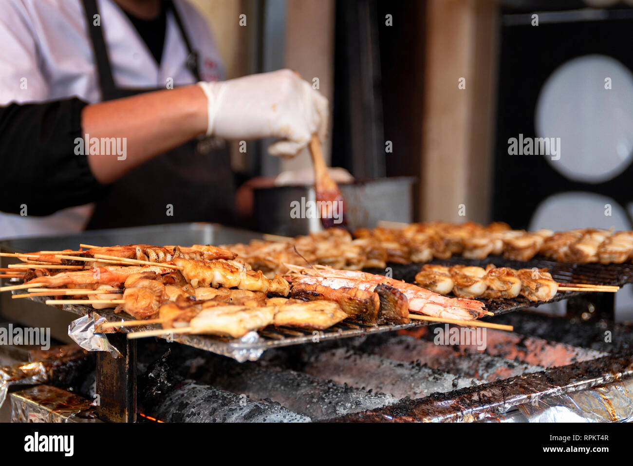 Street scene in Osaka, Japan, as chef bastes skewers of various meats for sale Stock Photo