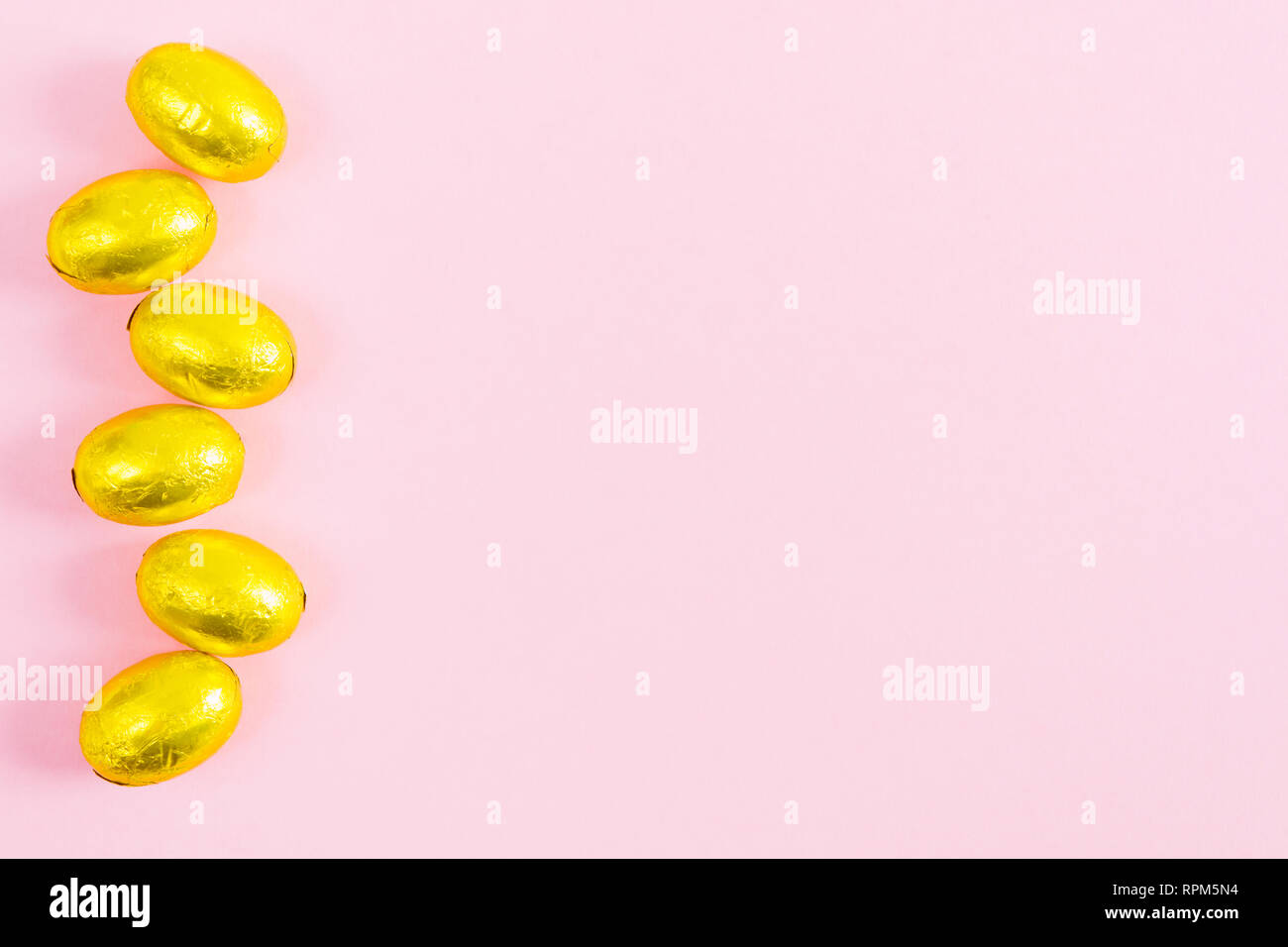 Golden easter eggs over pink background with copy space, flat lay style Stock Photo