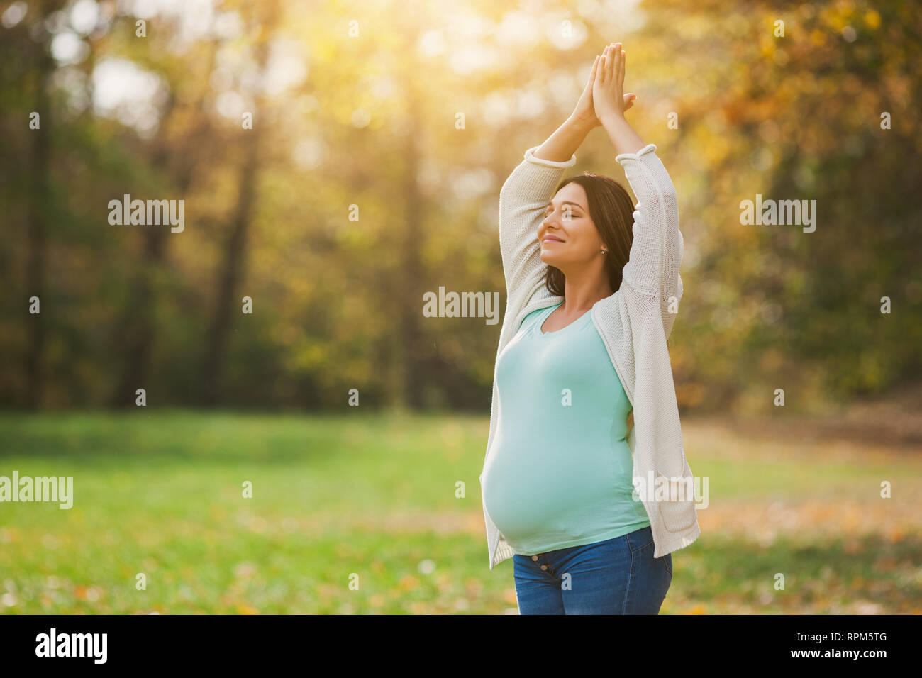 Pregnant woman relaxing in park. She is meditating. Stock Photo