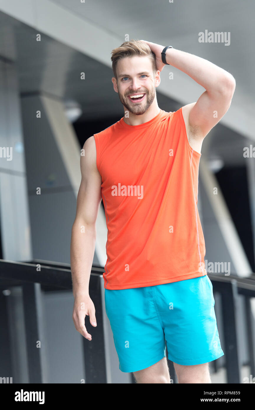 Man with bristle on smiling face in sporty wear, urban background. Sport  fashion concept. Man with beard or unshaven guy in stylish sport clothes.  Guy bearded and attractive cares about fashion Stock