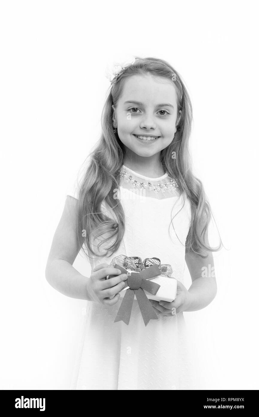 Boxing day concept. Girl smile with long blond hair isolated on white. Holiday gift and surprise. Birthday, anniversary celebration. Child hold present box and red bow. Stock Photo