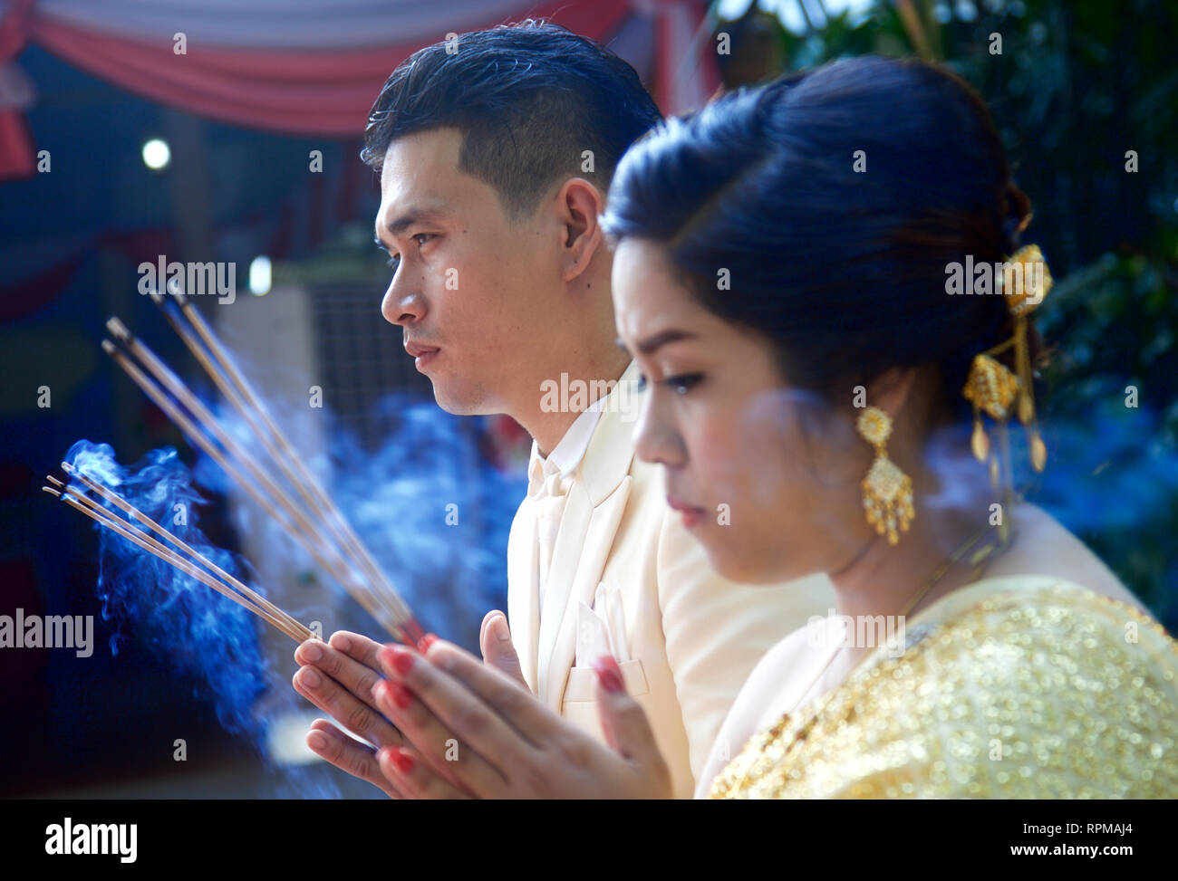 Newly wed couple saying prays to Buddha at their wedding in Thailand Stock Photo