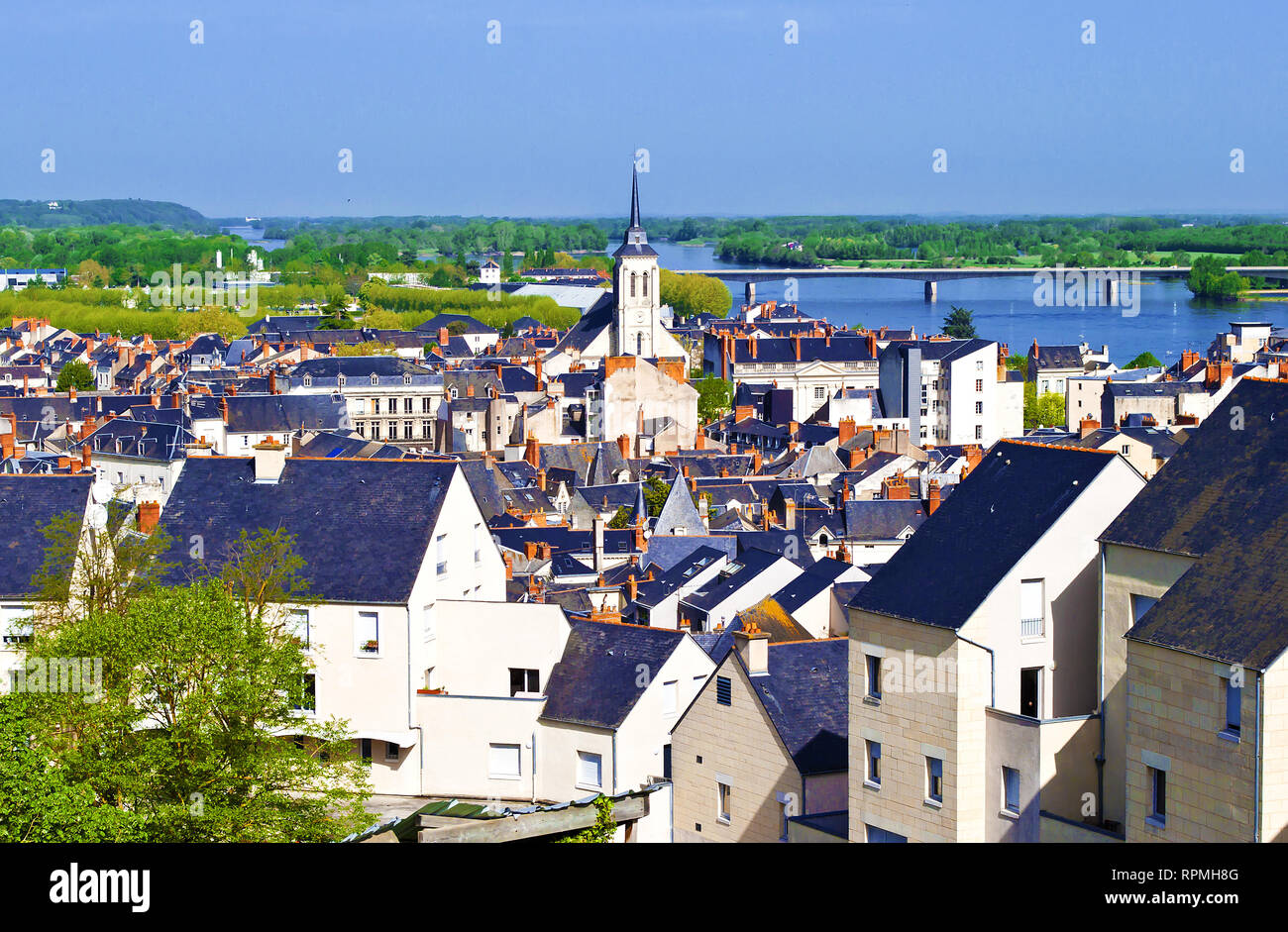 Breathtaking view on amazing small town Saumur, France. Many white and gray houses near a Loire river, arched bridge, lots of green trees and rooftops Stock Photo