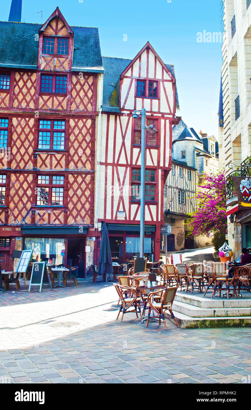 Eglise St Pierre square in solitary city center of a small town Saumur, France. Orange beam houses near a square with cafes and many chairs on a warm  Stock Photo