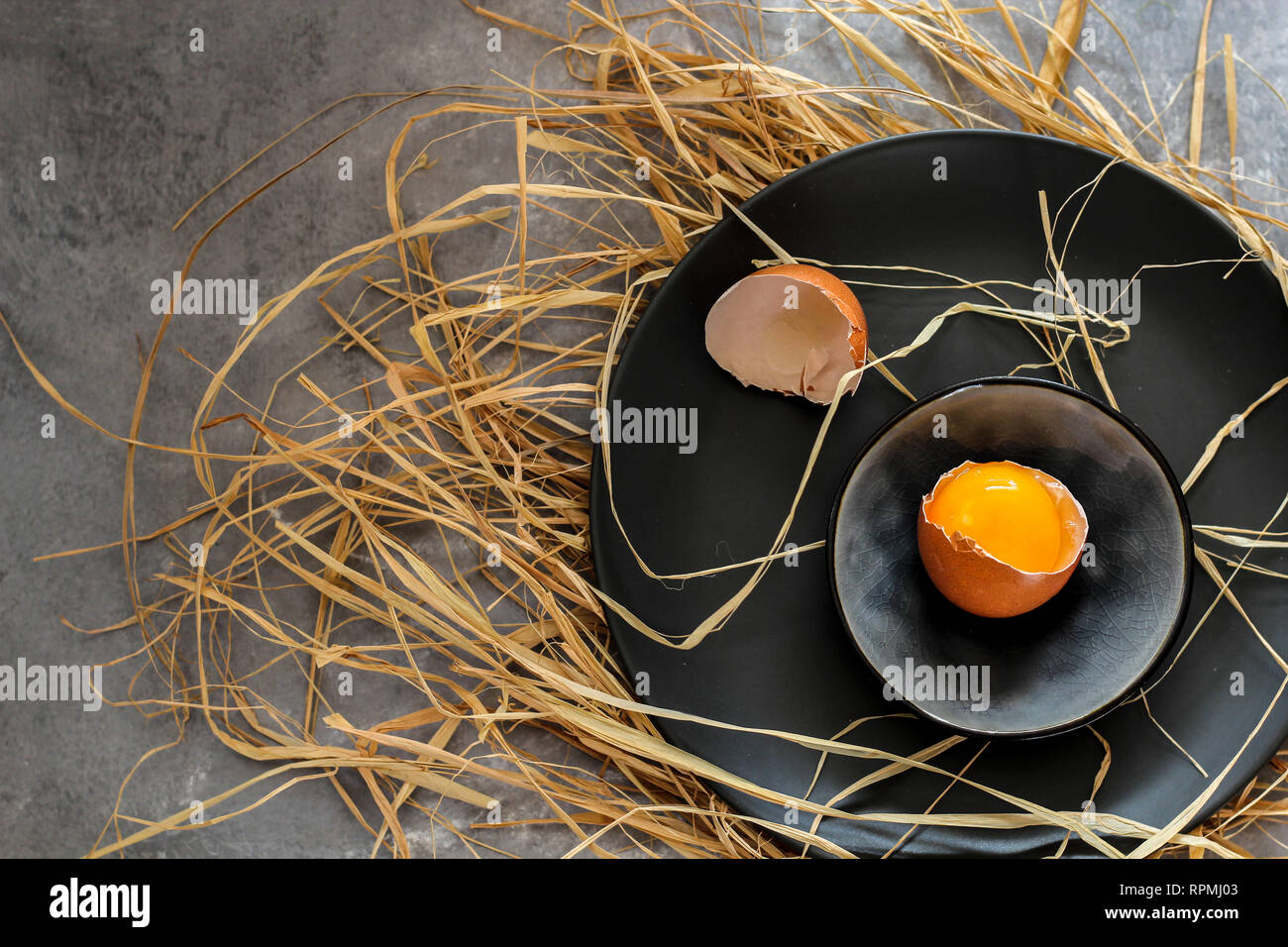Broken egg on a dark plate on a dark background Stock Photo