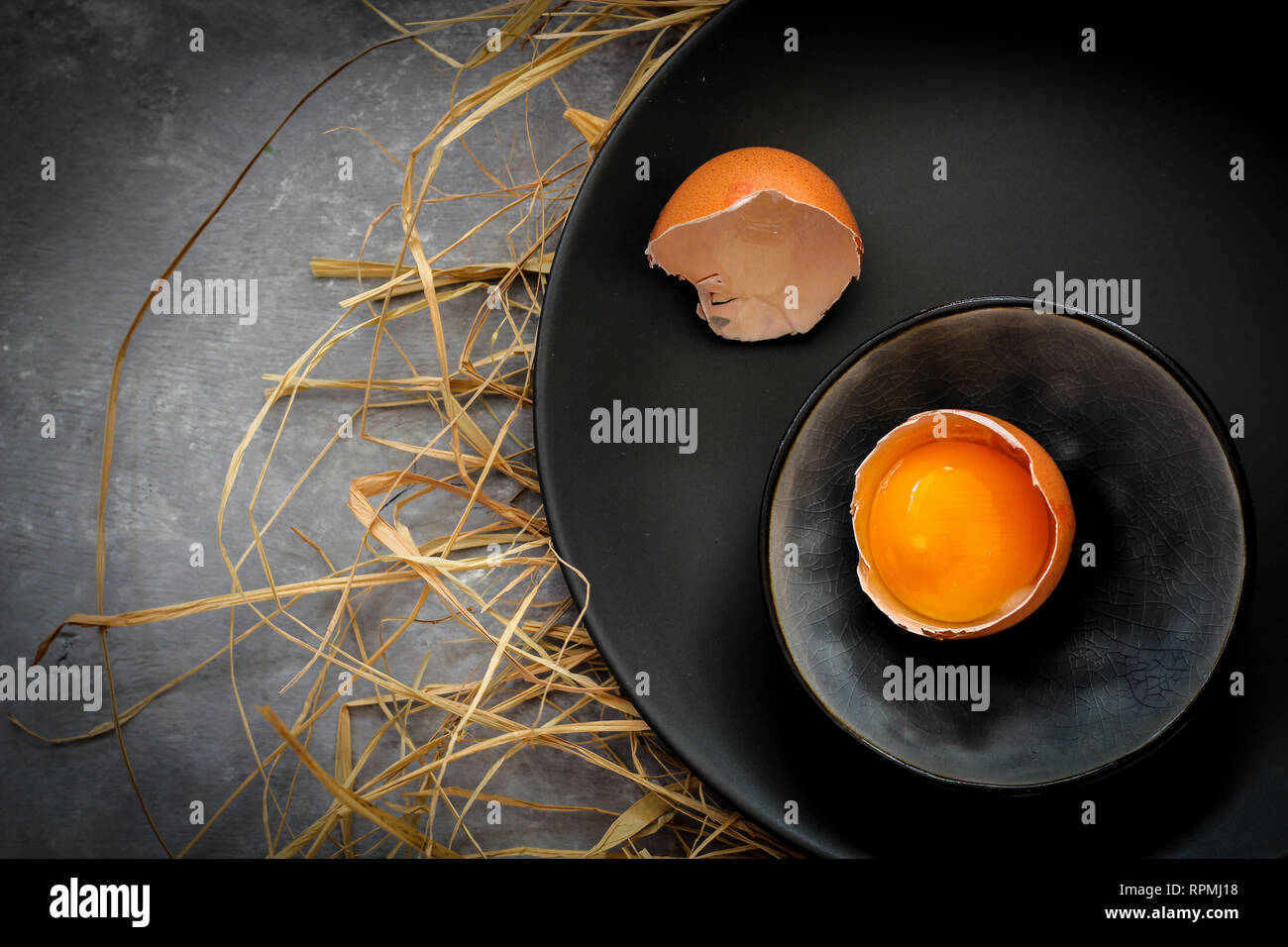 Broken egg on a dark plate on a dark background Stock Photo