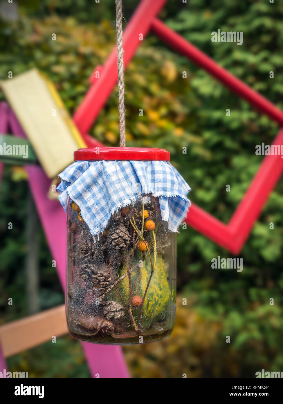 Old glass jar with organic decorations hanging on string in the garden Stock Photo