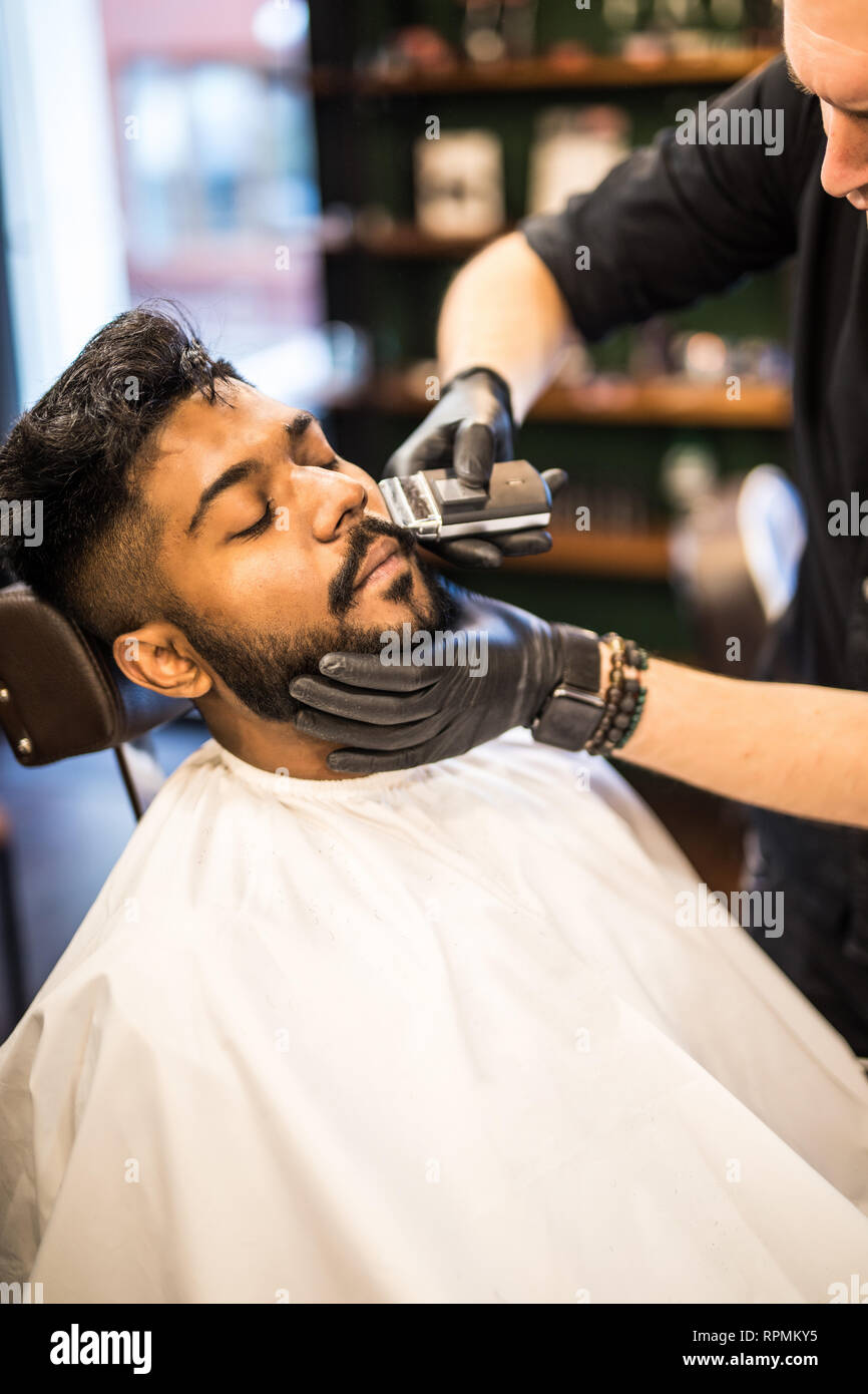 Close Up Side View Of Young Bearded Man Getting Beard Haircut By