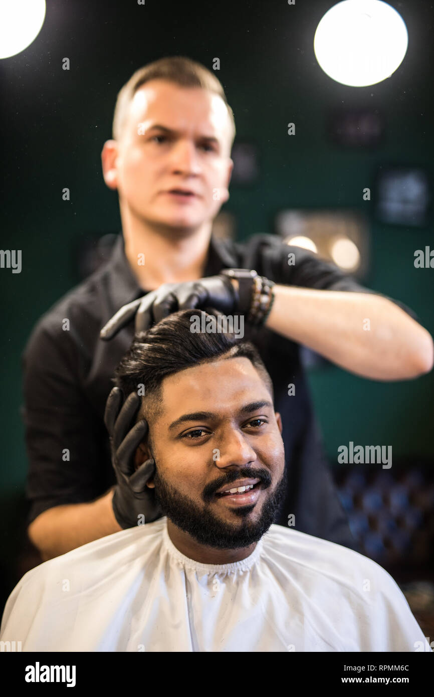 Barbers hand spread talcum powder on clients neck with professional shaving brush in barbershop salon.Male beauty treatment concept.Young black man ge Stock Photo