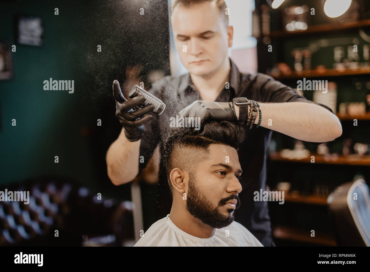 Barbers hand spread talcum powder on clients neck with professional shaving brush in barbershop salon.Male beauty treatment concept.Young black man ge Stock Photo