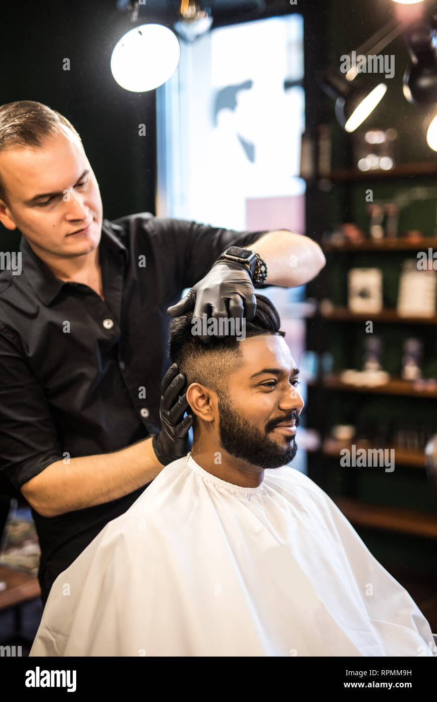 Barbers hand spread talcum powder on clients neck with professional shaving brush in barbershop salon.Male beauty treatment concept.Young black man ge Stock Photo