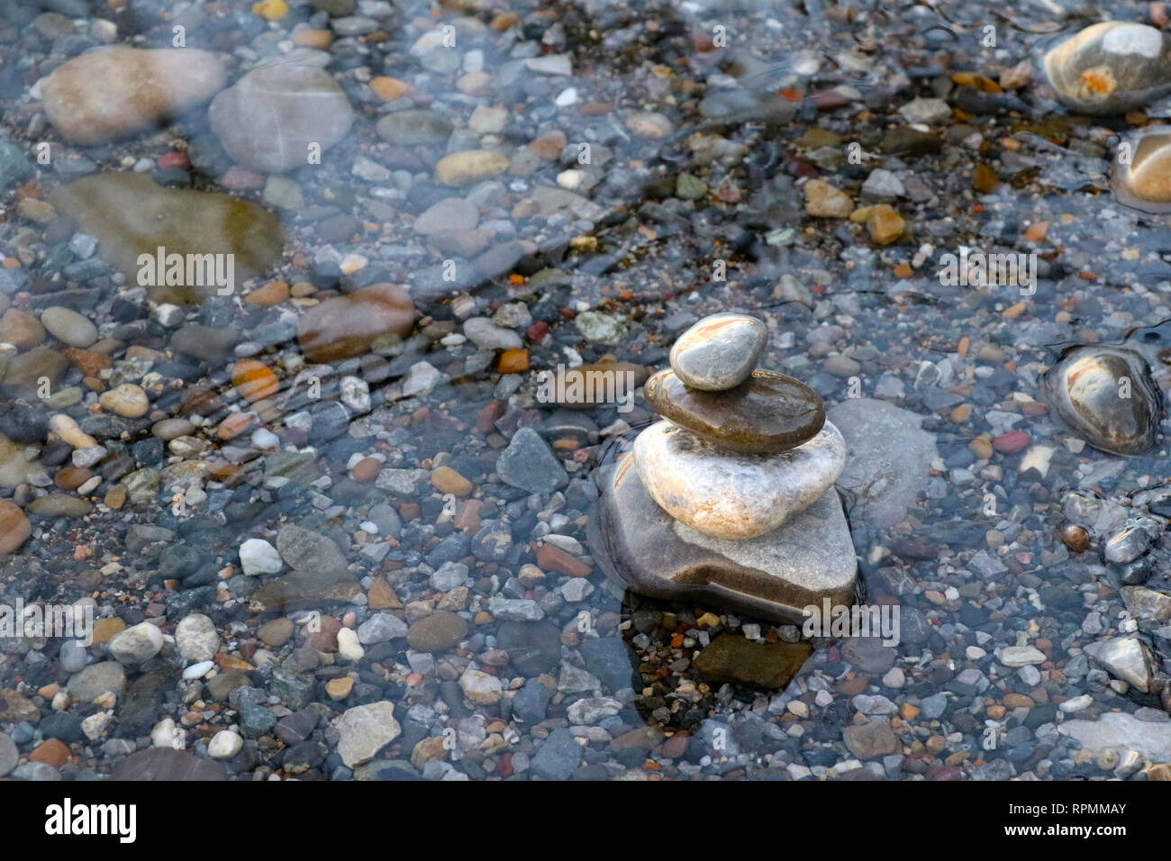 Stones piled up on the shore of a lake with stones in the background Stock Photo