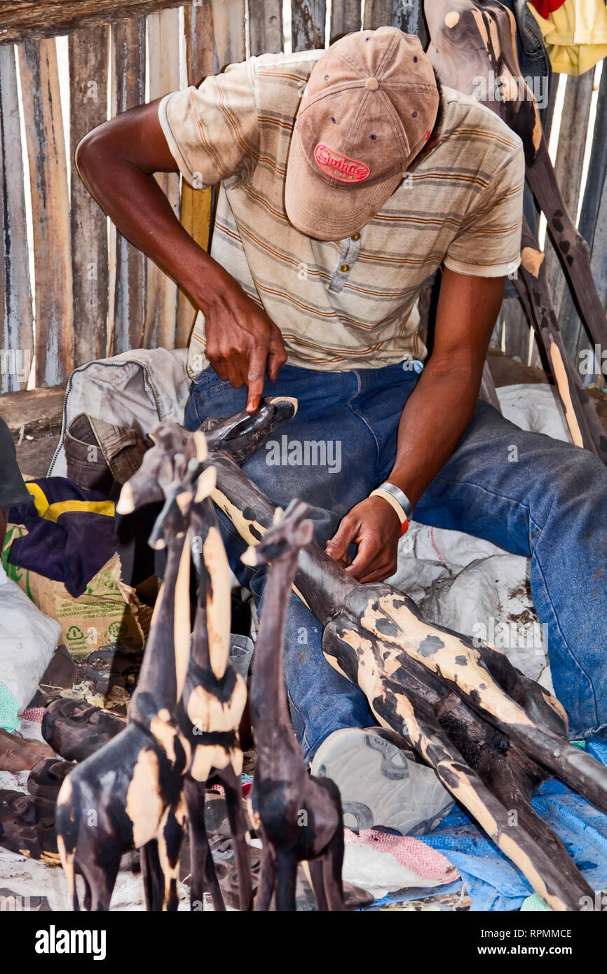 man carving ironwood; giraffe shapes; skilled artisan, working; occupation; job, art, Tanzania; Africa; vertical Stock Photo