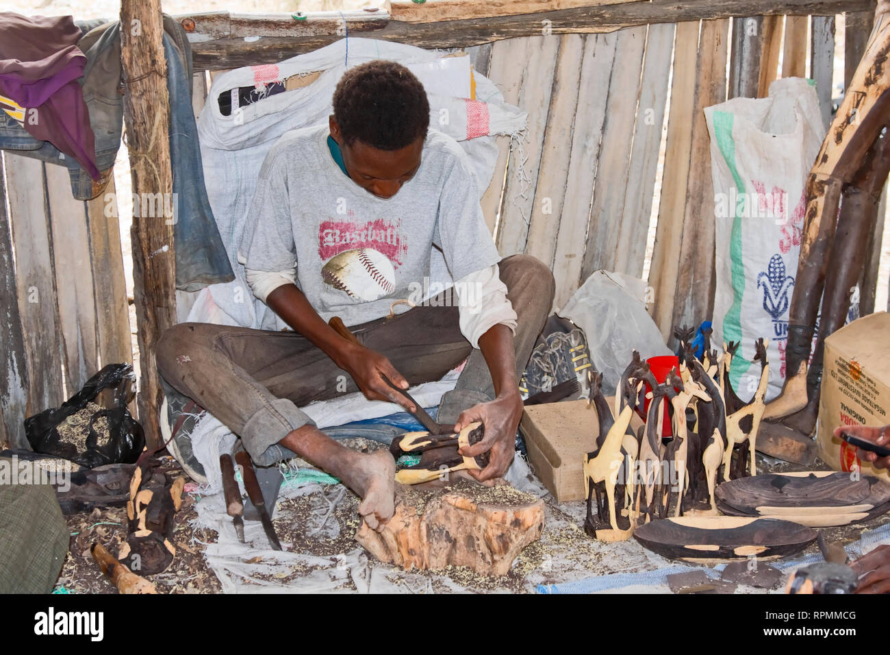 man carving ironwood; giraffe shapes; skilled artisan, working; occupation; job, art, Tanzania; Africa; horizontal Stock Photo