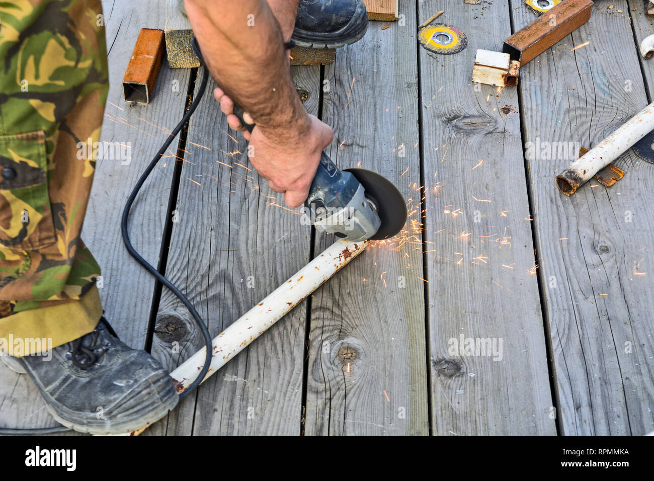 Metal working with an electric grinder in open space. Preparation for