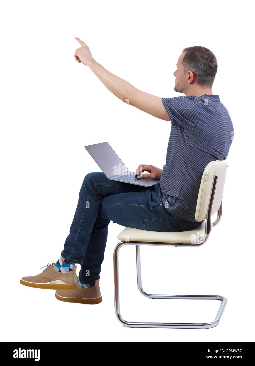 Side View Of A Man Who Sits On A Chair With A Laptop And Points With 