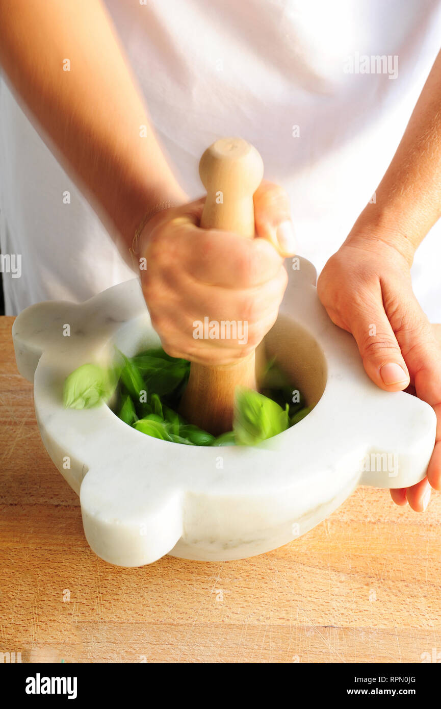 Traditional mortar-and-pestle pesto making with fresh DOP Genoese basil. Stock Photo