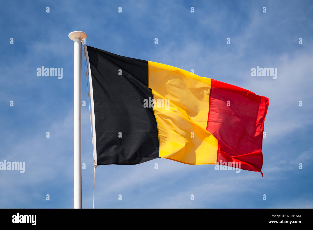 Flag of Belgium waving on wind over blue cloudy sky background Stock Photo