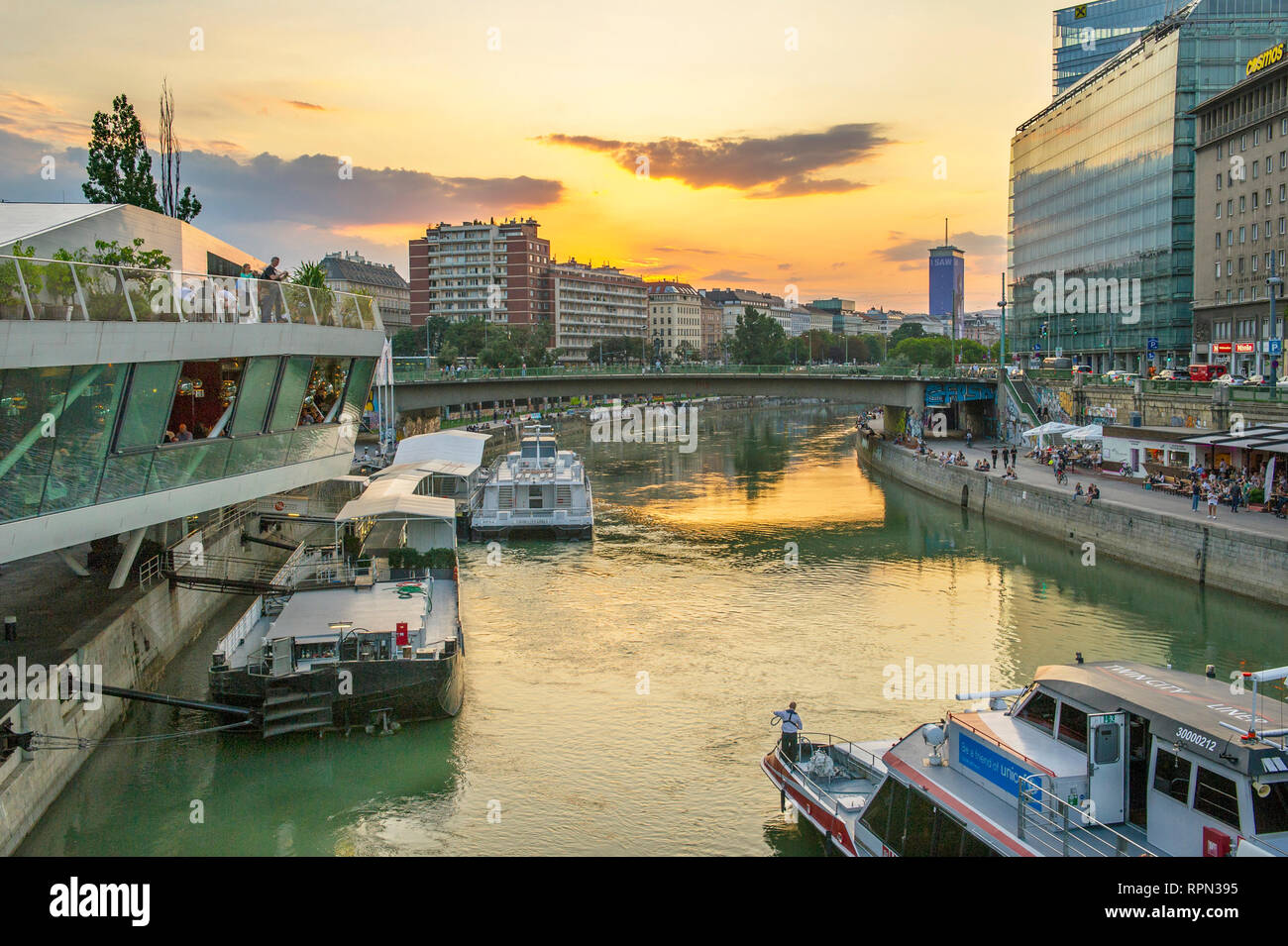 Riverboats and cafes along the Danube canal (Donaukanal) at sunset, close to Schwedenplatz, Vienna, Austria Stock Photo