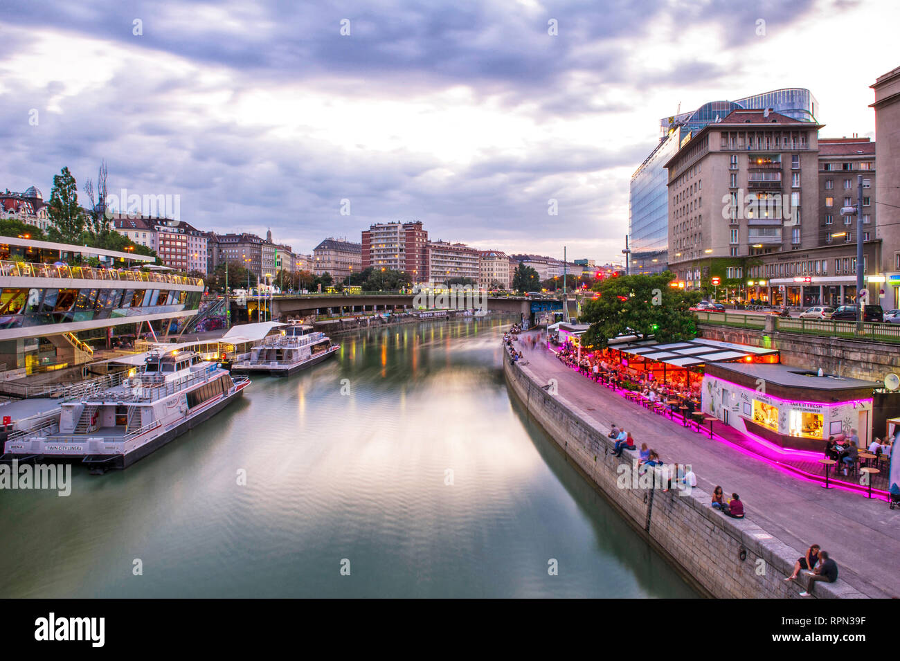 Riverboats and cafes along the Danube canal (Donaukanal) at sunset, close to Schwedenplatz, Vienna, Austria Stock Photo